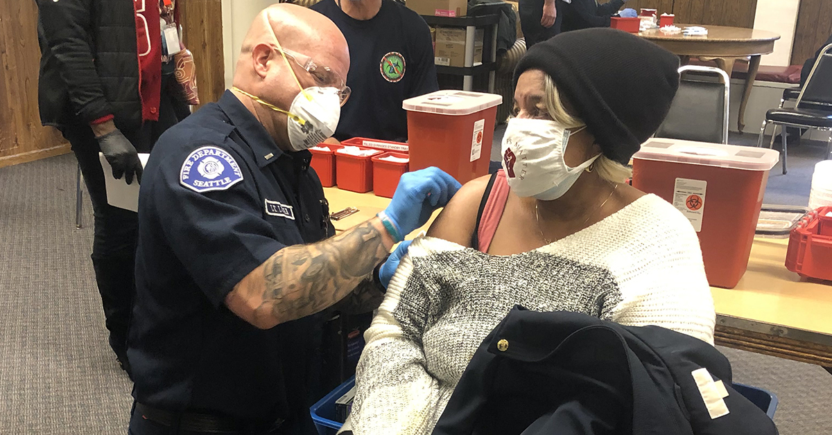 Woman receiving vaccine from Seattle fire fighter at a pop-up clinic
