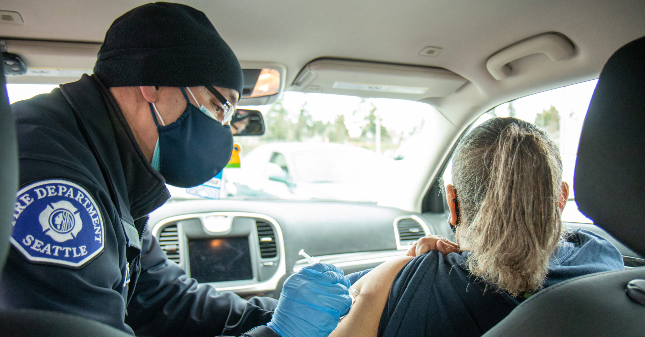 Person being vaccinated in their car by Seattle firefighter